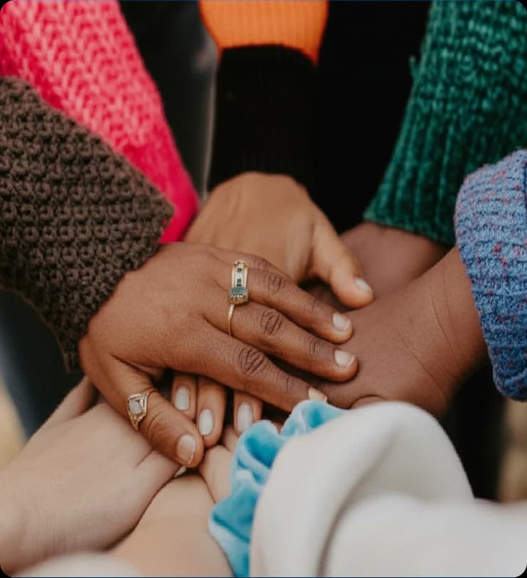 Primer plano de manos diversas colocadas juntas en señal de apoyo, representando la colaboración y la atención de salud humanitaria en contextos de crisis.