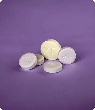 Pilules de mifépristone et de misoprostol présentées sur un fond violet représentant le contenu d'une formation sur l'avortement médicamenteux.